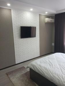 una camera con letto e TV a parete di Квартира a Shymkent