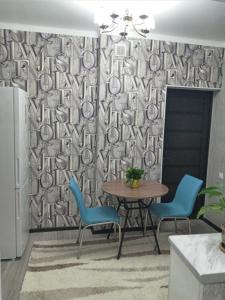 - une salle à manger avec une table, des chaises et un rideau dans l'établissement Квартира, à Chimkent