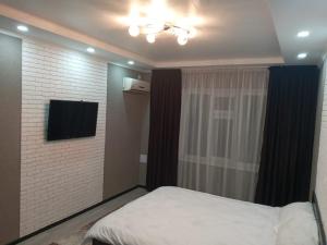 Dormitorio pequeño con cama y TV en Квартира en Shymkent