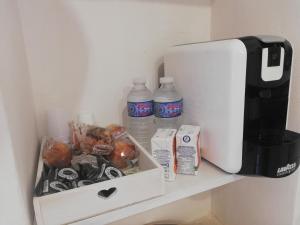 a shelf with a coffee maker and some food and water at SANTEA CASA vacanza in Grottaglie