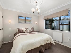 a bedroom with a large bed and a window at Heathcote Cottage - Taupo Holiday Home in Taupo