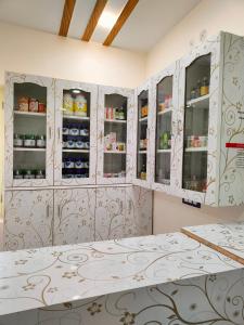 una cocina con armarios blancos y estanterías con comida en Krishnabalram Polyclinic Ayurveda centre en Rishīkesh