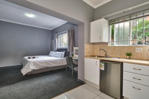 um quarto com uma cama e uma cozinha com um lavatório em Inn & Out Sandton em Joanesburgo