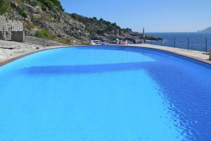 a large blue swimming pool next to the ocean at Villa Conchiglia, Massa Lubrense in Massa Lubrense