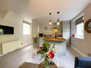 a living room with a kitchen and a table with flowers at Meadfoot Bay Apartment at Hesketh Crescent in Torquay