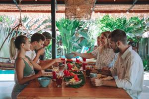 a group of people sitting around a table eating food at Seaside Tribe - Boutique Surf Stay & Retreat in Tanah Lot
