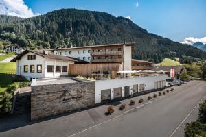 un edificio al lado de una calle con una montaña en Sporthotel Silvretta Montafon, en Gaschurn