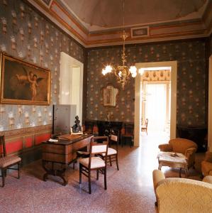 Habitación con mesa, sillas y un cuadro en la pared. en Palazzo Leuzzi B&B, en Galatone