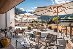 eine Terrasse mit Tischen, Stühlen und Sonnenschirmen in der Unterkunft Sporthotel Chalet in Gaschurn