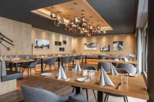 a restaurant with wooden tables and chairs and a chandelier at Sporthotel Chalet in Gaschurn