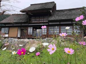 um campo de flores em frente a uma casa em もしもしの家 em Koshu