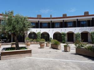 a building with a courtyard with potted plants at Logis Hôtel Restaurant Le Top du Roulier in Capendu