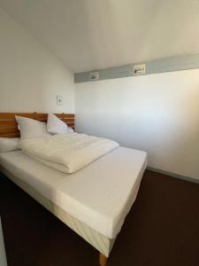 un letto con lenzuola e cuscini bianchi in una stanza di T2 mezzanine Seignosse Océan plein coeur du Penon a Seignosse