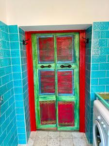 a red and green door in a blue bathroom at Mexican style chalett at lake Balaton in Kisapáti