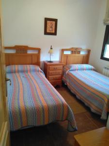 sypialnia z 2 łóżkami i drewnianą komodą w obiekcie Casa Rural el Maestro I w mieście Navalosa