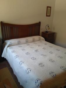 a bed with a white blanket with blue flowers on it at Casa Rural el Maestro I in Navalosa