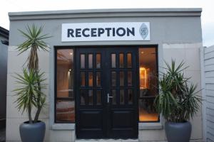 a store with a black door and two palm trees in front at The Eden Lodge Boksburg in Boksburg