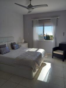 una camera con letto, ventilatore a soffitto e finestra di Modern Penthouse Sea View apartment Regina Gardens a Paphos