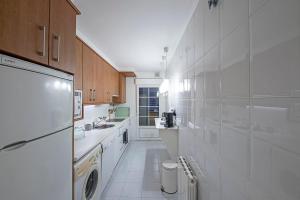 a white kitchen with a sink and a refrigerator at Apartamento Tíbula Sur Parking in Mérida