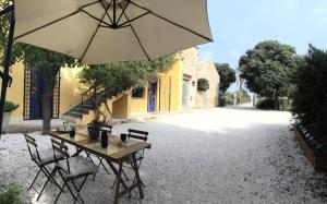 a table and chairs with an umbrella on a gravel road at Porta dei Mari in Ispica