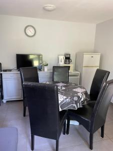 a dining room with a table and chairs and a clock at Les maisonnettes de bonneval in Jaujac