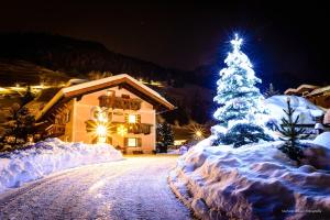 a christmas tree covered in snow in front of a house at Cesa Mandi e Miky in Canazei