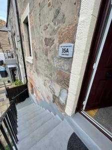 a sign on the side of a brick building with stairs at Albert Road Apartment in Eyemouth