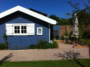 a blue shed with a patio and an umbrella at Chambres d'hôtes Le Mont d'Anon in Goviller