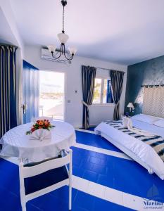 a blue room with two beds and a table at Marina Cap Monastir- Appart'Hôtel in Monastir