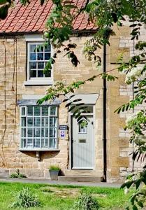 a brick house with a white door and windows at Lavender Cottage, Grade 2 Listed Period Stone Built Cottage In Pickering, North Yorkshire in Pickering