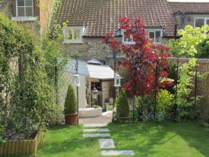 a garden with a fence and a red tree at Lavender Cottage, Grade 2 Listed Period Stone Built Cottage In Pickering, North Yorkshire in Pickering