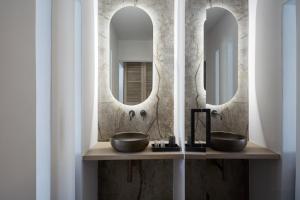a bathroom with two sinks and two mirrors at Kosmoplaz Beach Hotel in Platis Yialos Mykonos