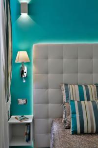 a bedroom with a white headboard and a blue wall at Apartments Amalfi Design in Amalfi