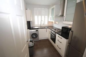 a kitchen with a washing machine and a washer at Harrow Place- Stylish Two Bedroom Apartment. in Harrow