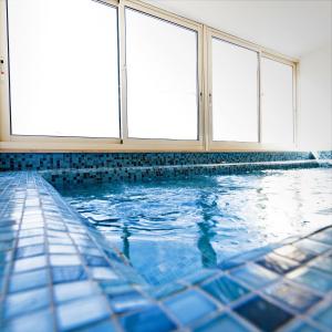 a swimming pool with blue tiles and windows at Bayview Hotel by ST Hotels in Il-Gżira