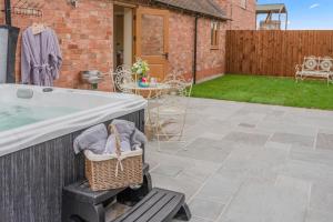 a patio with a hot tub and a basket at Swifts Retreat in Bidford