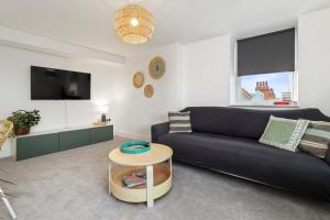 a living room with a black couch and a table at SkyView Eastbourne 24 in Eastbourne