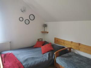 a bedroom with a bed with red pillows and a chair at Apartamenty Grosik in Krynica Zdrój