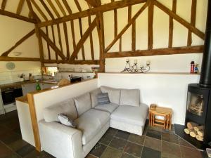 een woonkamer met een bank en een open haard bij The Hop Barn in Staplehurst