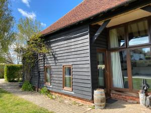 a house with black siding and a window at The Hop Barn in Staplehurst