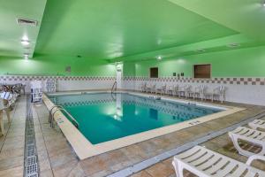 a large swimming pool with white chairs and tables at Comfort Inn & Suites in Lawrenceburg