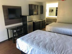 a hotel room with two beds and a kitchen with a tv at Suburban Studios North Charleston I-526 in Charleston