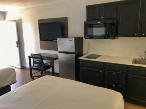 a kitchen with black cabinets and a refrigerator and a sink at Suburban Studios North Charleston I-526 in Charleston