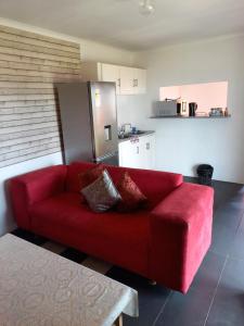 um sofá vermelho numa sala de estar com uma cozinha em 2 Bedroom Residential Home, along the coast. em Durban