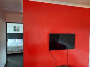 a red wall with a television in a bedroom at 2 Bedroom Residential Home, along the coast. in Durban