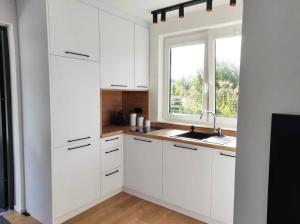 a kitchen with white cabinets and a window at Domek nad wodą Liliput in Jelenia Góra