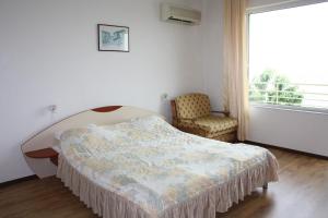 a bedroom with a bed and a chair and a window at Harmony Beach Family Hotel in Nesebar