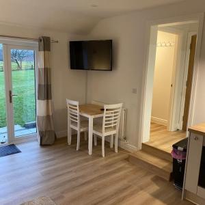 a dining room with a table and chairs and a television at Haven Oaks - Self contained rural lodge 2 in Shedfield