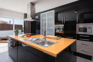 una cucina con armadi neri e lavandino in acciaio inossidabile di Luxury Villa Callao private heated pool Free Car except Christmas a Callao Salvaje Altre 22 foto