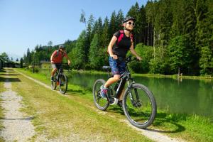 dos hombres montando bicicletas por un camino junto a un río en Appartement Fersterer/Schönblick, en Maishofen